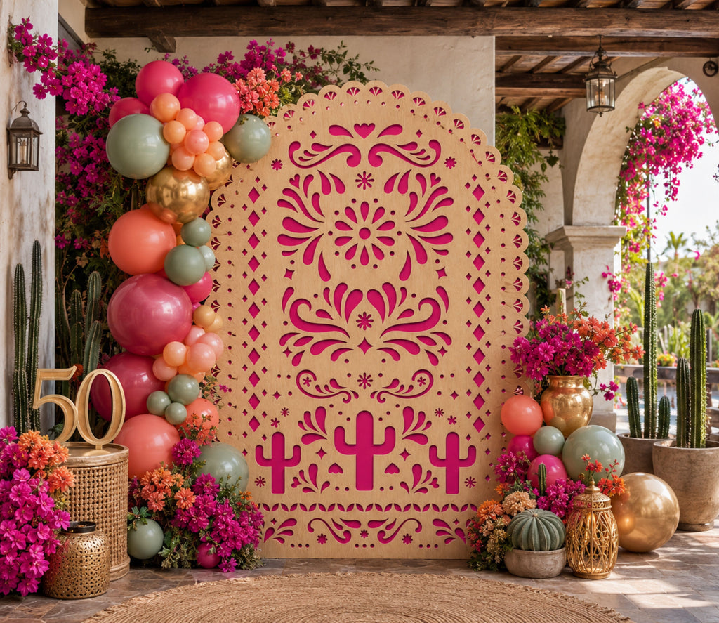 Pink and orange papel picado backdrop set with colorful flowers and balloons for Mexican celebration